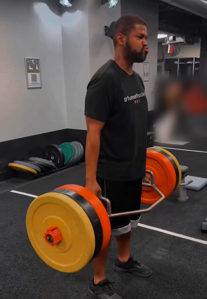 Garvin lifting a loaded trap bar at the gym